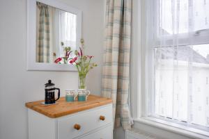 eine Kommode mit einer Vase neben einem Fenster in der Unterkunft Salty Cottage in Sidmouth + 22 Fotos