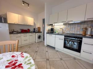 a kitchen with white cabinets and a tile floor at Schwalbenflug 1 Berlin in Berlin