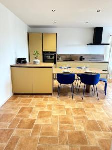a kitchen with tables and blue chairs in a room at Appartement Centre Ville in Porto-Vecchio