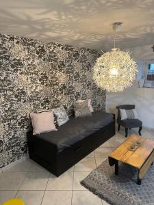 a living room with a black couch and a chandelier at Petite maison sur ferme 5min de la plage idéal professionnel in Trémel