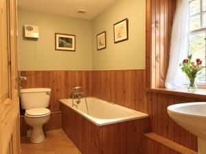 a bathroom with a tub and a toilet and a sink at The Coach House in Lochailort