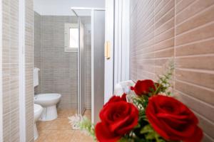a bathroom with a toilet and a bouquet of red roses at On The Beach San Foca in San Foca +13 photos