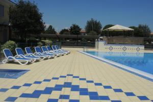 Una fila de tumbonas junto a una piscina. en Villaggio Tulipano, en Bibione