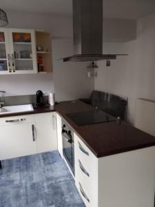 Una cocina con gabinetes blancos y una encimera negra. en Les mouflons, en La Bourboule