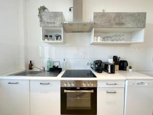 a white kitchen with a sink and a stove at Harmony Home - inkl Balkonen - TV Streaming - uvm in Bremerhaven