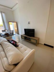 a living room with a white couch and a television at Casa confortável perto da praia in Guaratuba