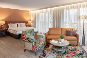 een hotelkamer met een bed, een bank en een stoel bij Valsana Hotel Arosa - Small Luxury Hotel in Arosa +51 foto's