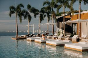 una mujer sentada en el borde de una piscina en un resort en Maxwell Collection Romantic Zone, en Puerto Vallarta