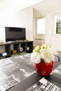 a red vase with white flowers sitting on a table at LA DEUCHE - Charmant Studio rénové avec vue in Chamalières