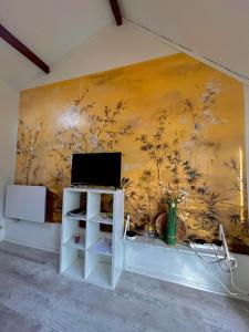 eine Wand mit einem Gemälde darauf und einem Fernseher in der Unterkunft Maisonnette 2 à 4 pers- Jardin privatif clôturé- Calme- Stationnement Gratuit- Pau Ouest Billère in Billère