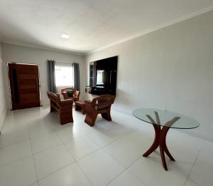 een woonkamer met een glazen tafel en stoelen bij Casa de Praia Temporada in Prado