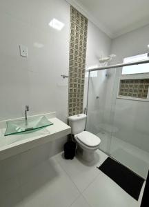 een badkamer met toilet en glazen douche bij Casa de Praia Temporada in Prado +3 foto's