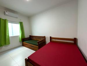 een slaapkamer met 2 bedden en een raam met groene gordijnen bij Casa de Praia Temporada in Prado