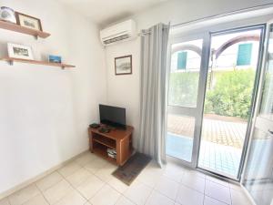 a living room with a television and a sliding glass door at Isca Dreams ID7 in Isca sullo Ionio