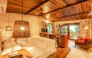 a bedroom with a bed and a desk and a chair at Hotel Ponta do Madeiro in Pipa