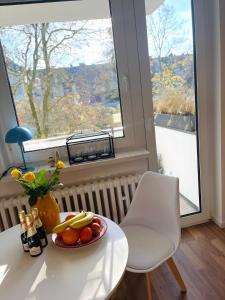 a white table with a plate of fruit and a window at Sunny Appartement in Düsseldorf +16 photos