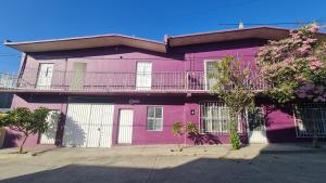 a pink house with a balcony on top of it at Departamento Añil in San Antonio de la Cal