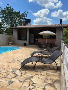 Un patio con sillas y sombrilla y una piscina. en Chácara Almeida, en Socorro