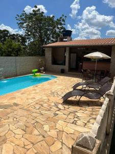 una piscina con dos sillas y una sombrilla en Chácara Almeida, en Socorro