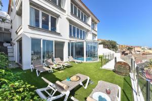 a backyard with a lawn with chairs and a table at Seaview Holiday Rental by VillaGranCanaria in Las Palmas de Gran Canaria