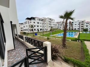 Un balcón de un edificio de apartamentos con una palmera en Lilac's Garden vue piscine, en M'diq