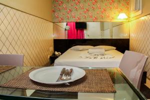 a room with a bed and a plate on a glass table at Hotel & Motel Henrique Dias (Adults Only) in Recife