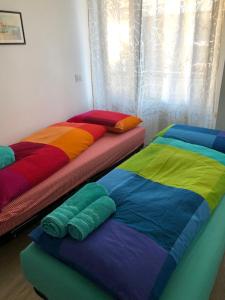 2 camas con sábanas de diferentes colores en una habitación en Casa Turchese, en Merano