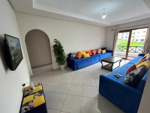una sala de estar con 2 sofás azules y una ventana en Lilac's Garden vue piscine, en M'diq