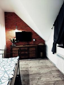 a living room with a brick wall and a television at Weranda in Orzysz
