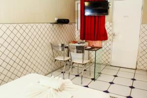 a bedroom with a bed and two chairs and a television at Hotel & Motel Henrique Dias (Adults Only) in Recife