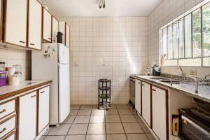 Una cocina con un refrigerador blanco y paredes de azulejos blancos. en Suíte da Casa da Mi, en Porto Belo 5 fotos más