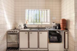 Una cocina con fregadero, estufa y ventana. en Suíte da Casa da Mi, en Porto Belo