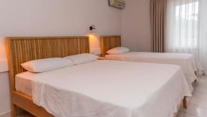 two beds in a hotel room with white sheets at Golden Lighthouse Hotel in Patara