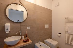 a bathroom with a sink and a mirror and a toilet at BACARìA DA DANTE Rooms in Bassano del Grappa