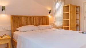 a bedroom with a white bed with a wooden headboard at Golden Lighthouse Hotel in Patara