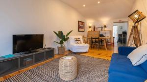 a living room with a tv and a blue couch at Pátio Vilareto - Villa Fernanda in São Domingos de Rana