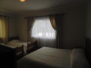 Habitación de hotel con 2 camas y ventana en Hostal Arrayan en Valdivia