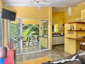 a kitchen with yellow walls and a sliding glass door at Casa Amable - Manuel Antonio in Quepos