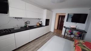 a kitchen with white cabinets and a black counter top at Steffi Apartment in Balş