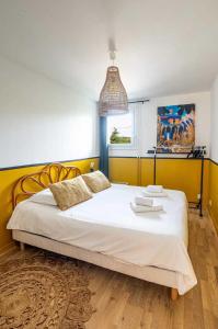 a bedroom with a large white bed with a yellow wall at Elegant 2 bedroom triplex with parking Honfleur in Honfleur
