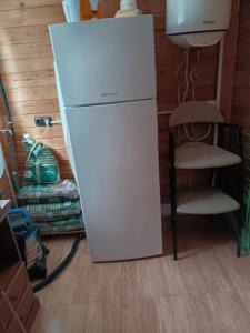 ein weißer Kühlschrank in einem Raum mit einem Stuhl in der Unterkunft La casita in Tarazona de la Mancha