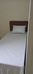 un letto bianco con un cuscino sopra di Pindorama 11 apartamento mobiliado, impecável! a Santos