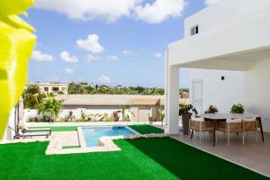 a house with a swimming pool and a green lawn at 3 bedroom luxury vacation villa for a relaxed intimate feeling in Willemstad