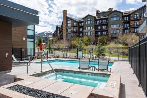 Una piscina con dos sillas al lado de un edificio. en Walk to Gondola, Heated Pool, Luxury Interiors, 2 Car Garage, Sleeps 12, Spacious Patio!, en Park City