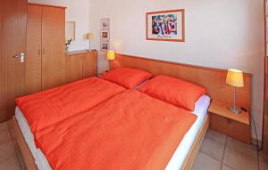a bedroom with an orange bed with two red pillows at Ferienwohnung Ueckermünde in Ueckermünde