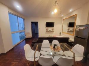 a living room with a glass table and white chairs at Pórtico tower in Cochabamba