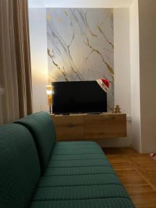 a living room with a green couch and a tv at Apartman Raj in Kraljevo