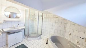 a bathroom with a tub and a sink and a shower at Gemütliche Ferienwohnung in Bodenmais I Sauna I Balkon I Blick Silberberg in Bodenmais +22 photos