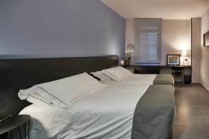 a bedroom with a large bed with white sheets and pillows at Smart Hotel in Carpi +49 photos