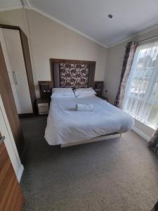 a bedroom with a large bed with white sheets and a window at Sea views, fabulous modern lodge in Port Seton